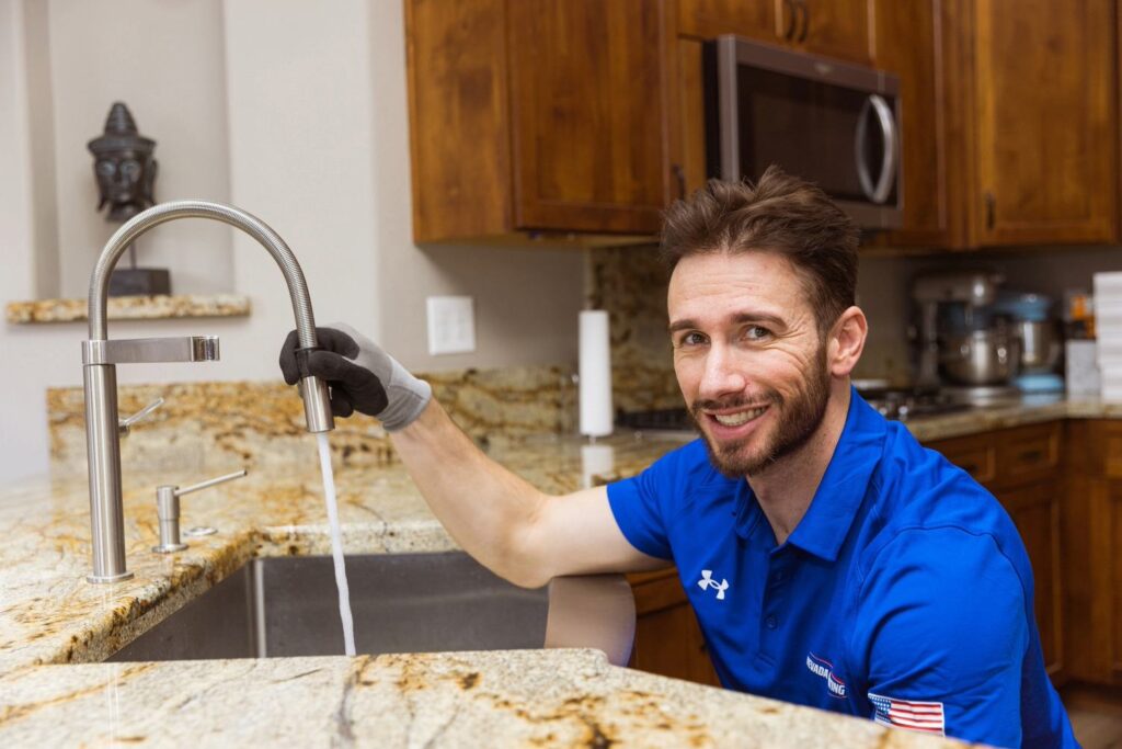 Goettl plumber checking for water flow at a faucet and smiling